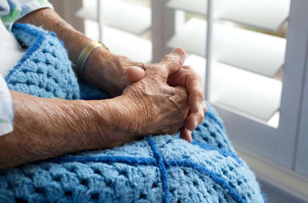 elderly hands resting on blanket